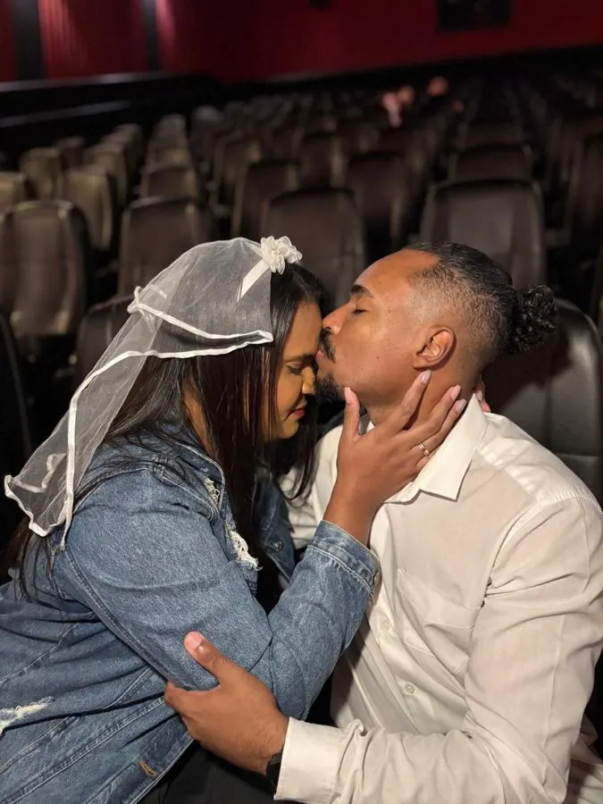Noivo beija a testa da noiva de véu no cinema