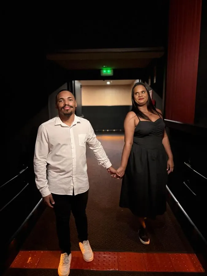 Casal de mãos dadas no corredor do cinema