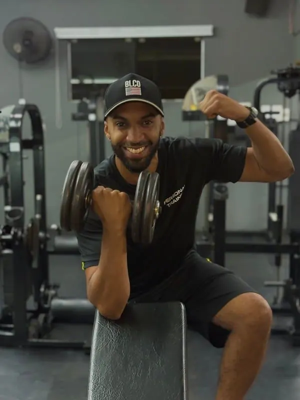 Personal trainer na academia, segurando halteres